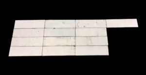 Set of 13 white glass tiles shown laid out in rows, with a plain rectangular shape and visible age-related scrapes and imperfections on the surface.