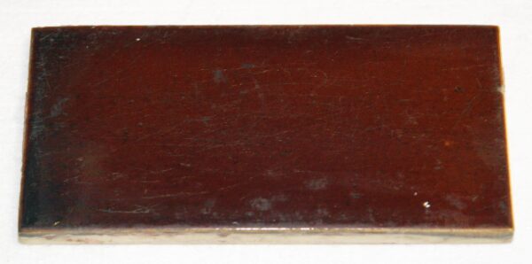 Rectangular brown ceramic subway tile with a worn surface and visible age-related scratches and chips.