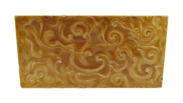 Decorative tan ceramic tile with a swirl pattern shown in close-up.