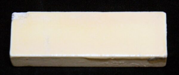 Antique pale yellow ceramic wall tile shown in a close-up front view with minor chips and age-related wear along the edges.