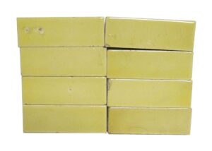 Set of eight yellow ceramic tiles with a crackled surface and visible age-related chips and scratches.