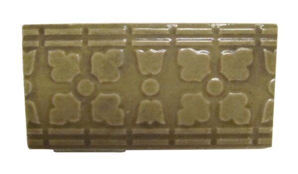 Tan ceramic decorative tile with a raised floral and geometric pattern shown in a close-up view.