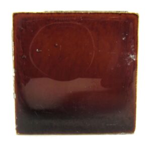 Brown ceramic square tile with visible age-related imperfections and minor chips along the edges.