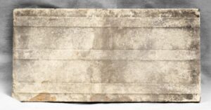 Rectangular ceramic decorative tile with aged wear and minor chips, shown in a close-up view of the full piece.