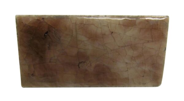 Close-up of a pink ceramic tile with a crackled surface and minor age-related imperfections.