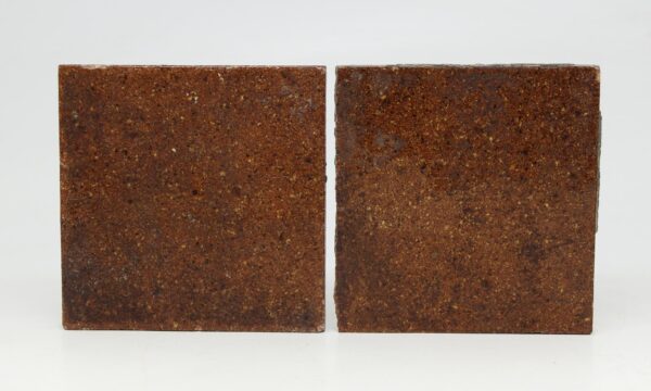 Pair of square brown ceramic tiles shown side by side, one slightly shorter with visible edge wear and small chips from age.
