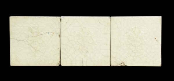 Three square white ceramic wall tiles with a crackled surface and visible age-related chips and wear, shown side by side.
