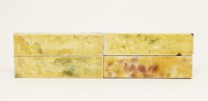 Set of six ceramic tiles with a shiny crackled glaze in yellow with purple and green areas, shown as four pieces in a two-by-two arrangement with minor age-related chips.