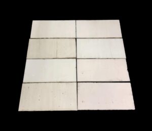 Square foot of thin white glass tiles arranged in a grid, shown with a plain surface and visible age marks and scrapes.