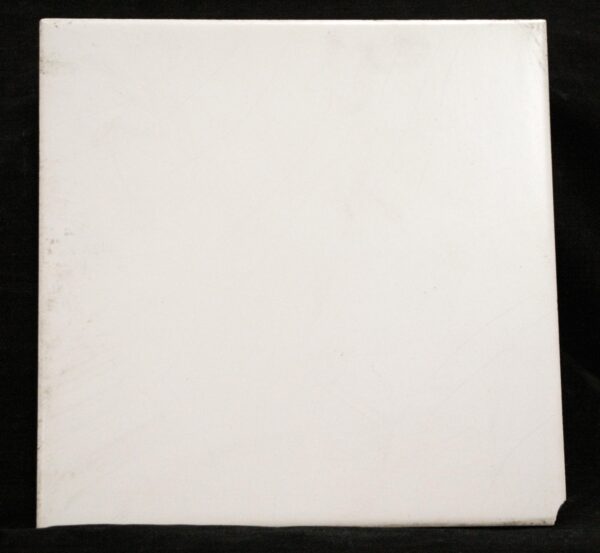 Square ceramic wall tile with a plain white beveled surface, shown front-facing with minor age-related chips and scuffs visible along the edges.