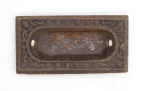 Victorian recessed window sash lift with an oval handle and ornate rectangular border, shown in a close-up top view.