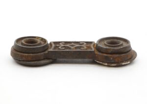 Antique Victorian cast iron window shutter latch shown in a close-up view, with two round end fittings connected by a decorative central bar and visible age wear.