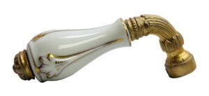 Ornate white porcelain and brass faucet handle with a curved brass stem and decorative end cap.