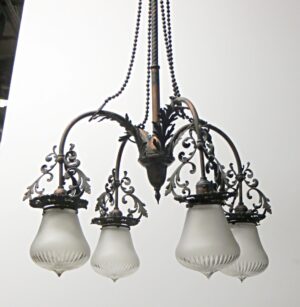 Victorian four-arm chandelier with ornate scrollwork, four frosted glass shades, and a beaded chain hanging from the center.