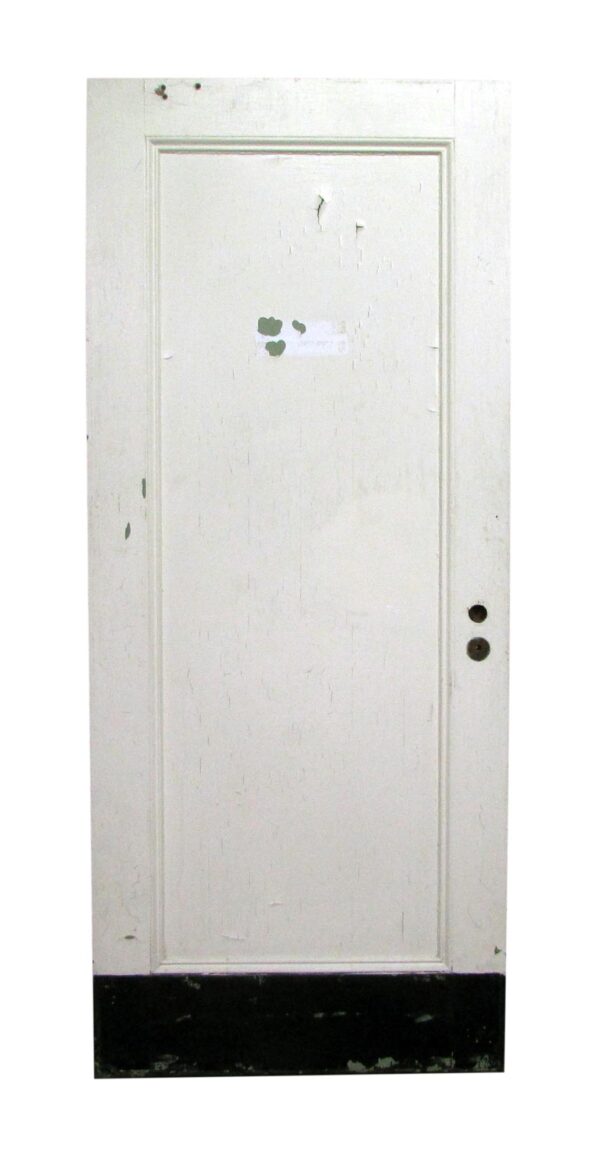 White one-panel wooden door with a raised rectangular inset, visible paint wear, and two bore holes on the right edge.