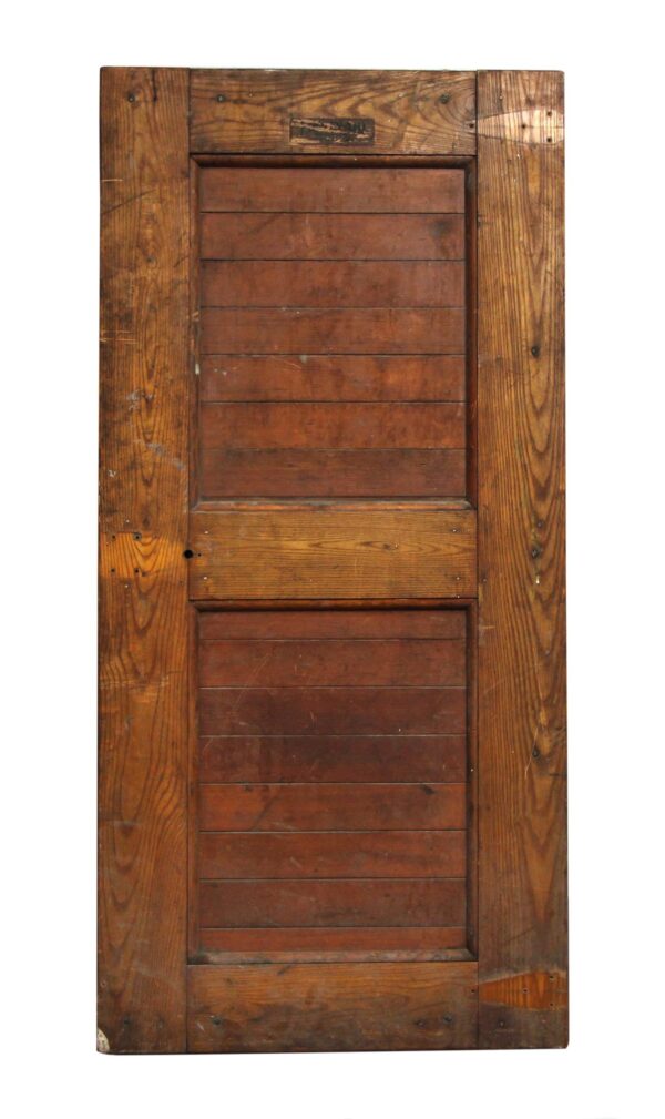 Front view of a two-panel wooden door with visible wear and no hardware attached.