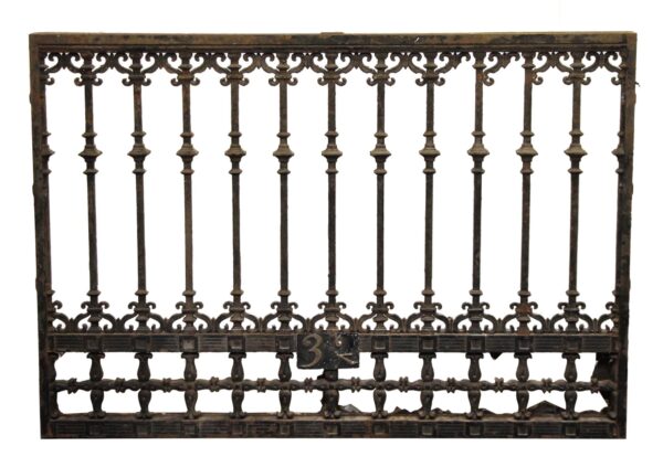 Antique cast iron panel with decorative scrollwork and vertical bars, shown front on with a numbered plate near the lower center.