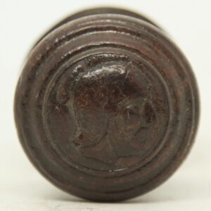 Close-up of a round wooden door knob with a Greek head rosette design in a dark wood tone, shown from the front.