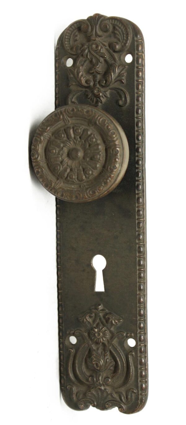 Antique bronze door knob and backplate with floral detailing and a keyhole opening.