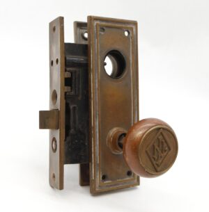 Antique bronze mortise lock set with back plate and round knob showing an LN emblem.