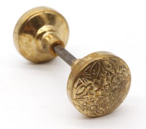 Pair of ornate bronze door knobs with a spindle, one showing a detailed floral pattern and the other a plain back view.