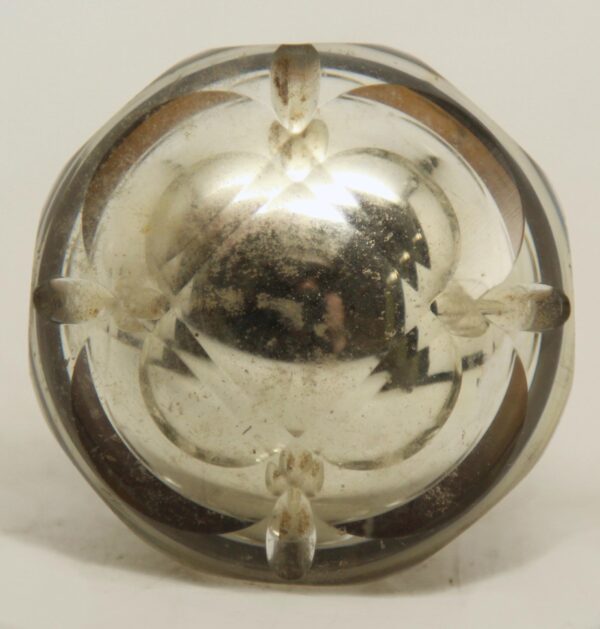 Close-up of an antique mercury glass passage door knob with faceted detailing, a wide brass shank, and visible surface wear.
