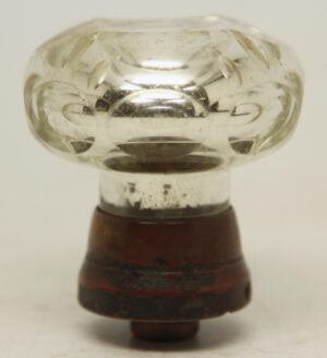 Antique faceted passage door knob made of clear and silver mercury glass with etched details and a wide brass shank, shown in close-up.