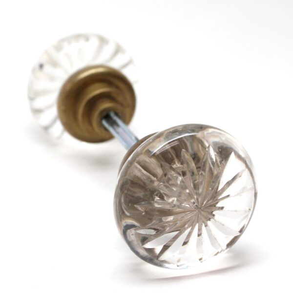 Clear cut glass door knob with an antique brass shank and spindle, shown in close-up to reveal the faceted star pattern.