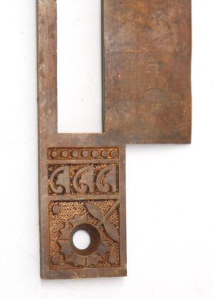 Ornate brass faceplate cover for an antique mortise lock, shown with a rectangular cutout and decorative geometric engraving at one end.