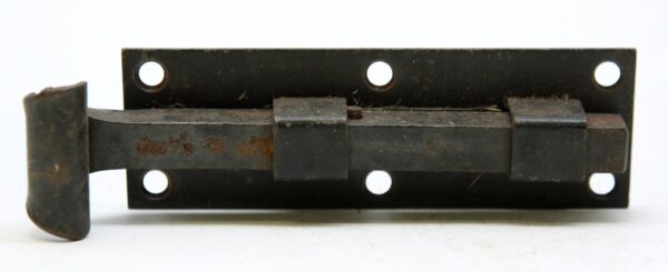 Vintage iron door bolt with a black surface and rectangular mounting plate, shown with the sliding bolt extended and no catch included.