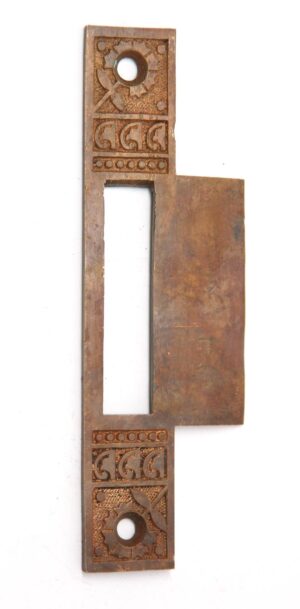 Ornate brass strike plate cover with an elongated rectangular opening and decorative geometric engraving at both ends.
