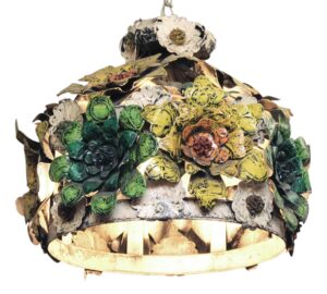 Decorative metal floral light with layered painted flower forms in multiple colors and a rounded open frame, shown in close-up from below.