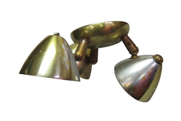 Three-light brass flush mount spotlight fixture with three swivel heads shown angled in different directions.