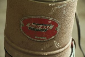 Close-up of a vintage photo enlarger with a worn Federal of Brooklyn label and visible surface wear.
