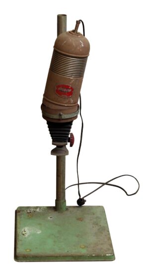 Vintage metal photo enlarger with a brown housing, green base, power cord, and visible wear.