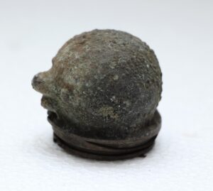 Small round doll head mold made of cast iron, shown in a close-up view with a domed top and small protruding nose.