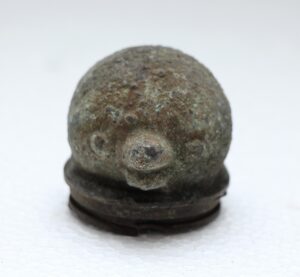 Close-up of a small round cast iron mold with a weathered surface and domed top.