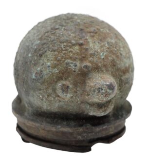Close-up of a small round cast iron doll head mold with a textured, weathered surface and a flat base.