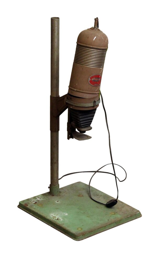 Vintage metal photo enlarger with a brown head, green base, and attached power cord, showing visible wear.