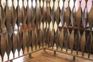 Mid century modern room divider with alternating pod-shaped bronze panels in a long freestanding frame.