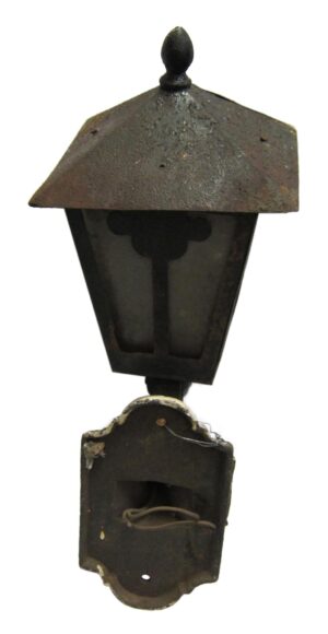 Arts and Crafts wrought iron exterior wall sconce with a peaked top, glass front, and lower mounting plate, shown in a close-up view.