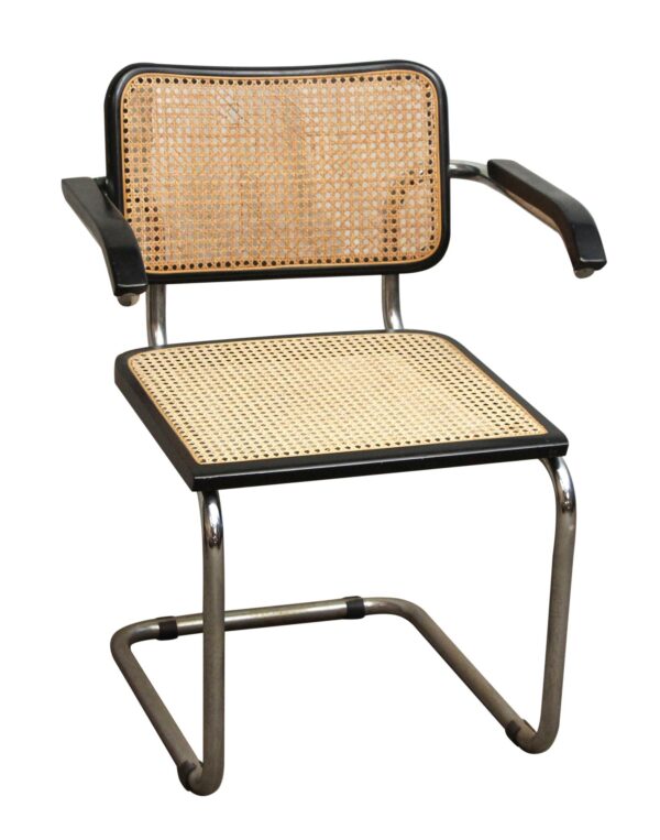 Mid century cane chair with a black metal frame, tan wicker seat and back, and armrests.