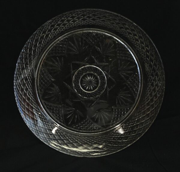 Clear glass plate with a cut pattern and a central starburst design, shown from above.