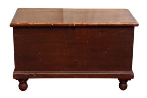 Dark wood cedar chest with a worn top, front panel, and ball feet, shown in a straight-on view.