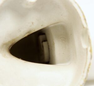 Close-up of a white porcelain wall sconce base with a milk glass shade opening and visible rounded screw detail.