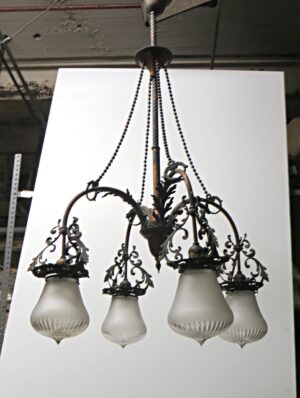 Victorian four-arm chandelier with ornate scrollwork, four frosted glass shades, and a hanging chain.