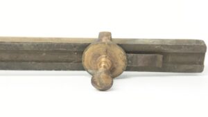 Antique brass commercial door pull shown in close-up with a round center mounting hub and one handle end visible.