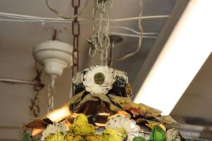 Close-up of a multicolor metal floral light with layered painted petals and hanging chain details.