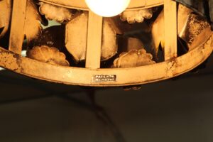 Close-up of a floral metal light with applied petal details and a visible patent label on the rim.