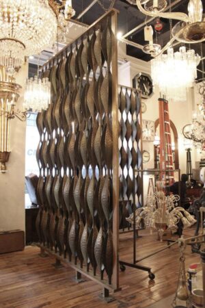 Mid-century modern room divider with alternating pod-shaped bronze panels in a solid frame, shown as a freestanding section on supports.